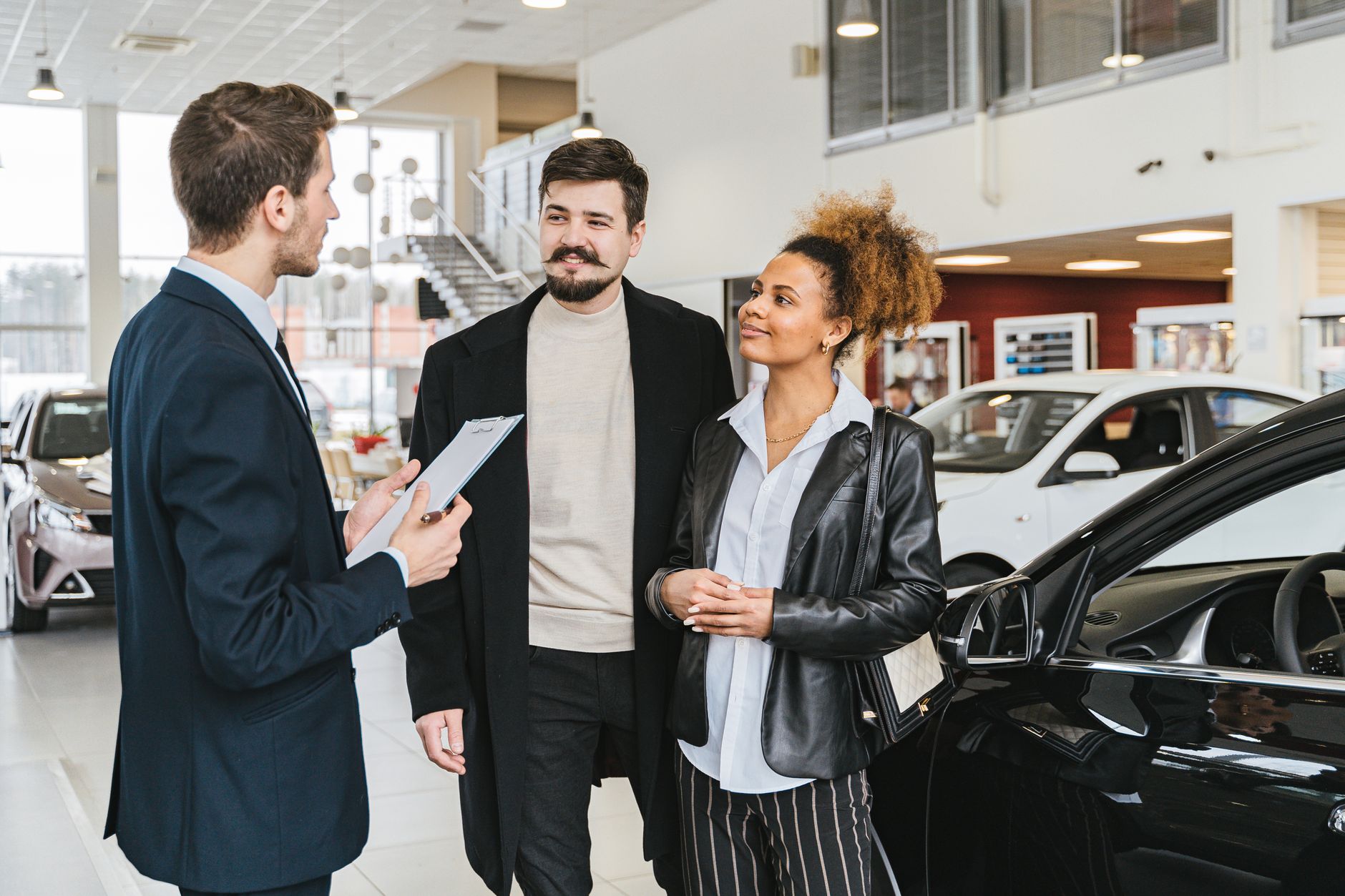 Vendedores e clientes conversando em um showroom de carros